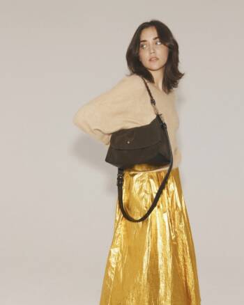 Modèle portant le sac Le New Benson en velours noir Ebony Herbert Frère Sœur, avec une jupe dorée et un pull crème