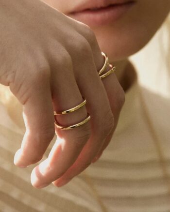 Main féminine portant la bague double anneau doré Eve BDM Studio, vue rapprochée sur fond crème
