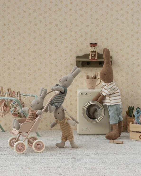 Scène Maileg représentant une famille lapins autour d’une machine à laver, avec un landau poussé par deux petits lapins dans une chambre au décor floral.