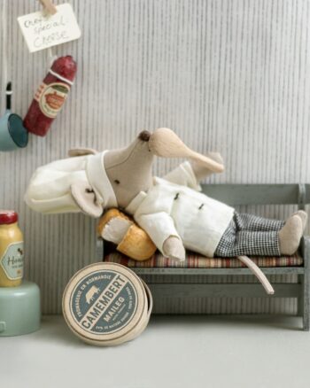 Souris Chef cuisinier Maileg allongée sur un banc avec camembert miniature et accessoires de cuisine