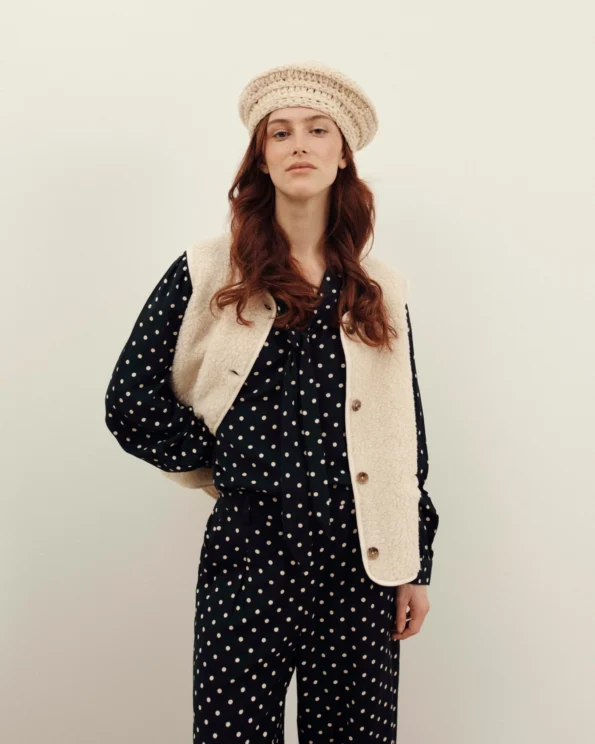 Femme portant le gilet Sherpa sans manches Emile et Ida avec béret et combinaison noire à pois
