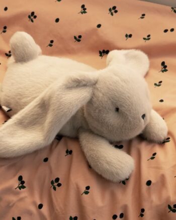 Peluche lapin lestée Paulin Mist Liewood sur une housse de couette imprimée