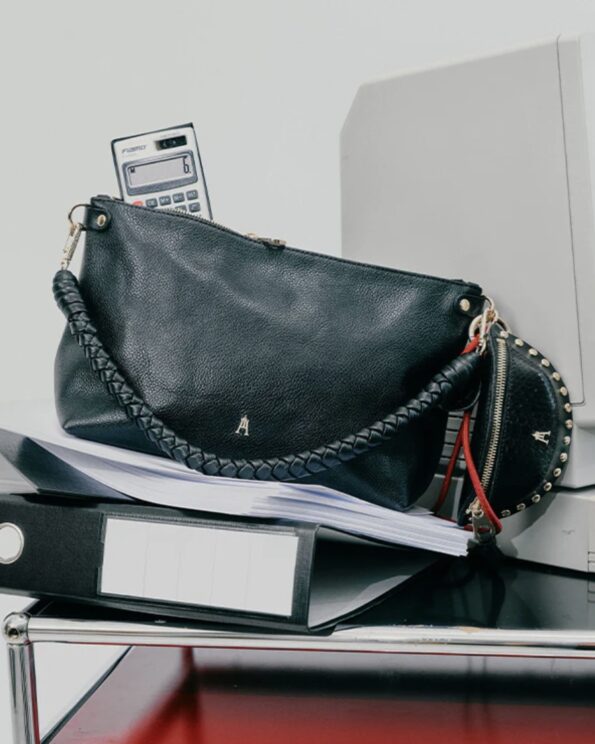Mallow Twist Grainé Noir Craie Studio – Sac en cuir avec poignée tressée et chaîne dorée posé sur un bureau