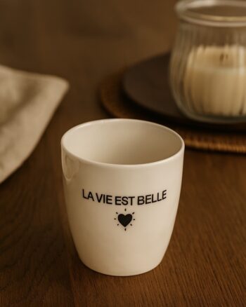 Gobelet message La vie est Belle Opjet Paris en faïence, posé sur une table avec ambiance chaleureuse