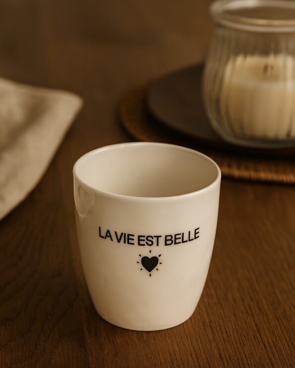 Gobelet message La vie est Belle Opjet Paris en faïence, posé sur une table avec ambiance chaleureuse