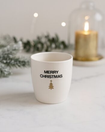 Gobelet Merry Christmas doré – Opjet Paris en faïence blanche sur table en marbre, ambiance chic et festive.