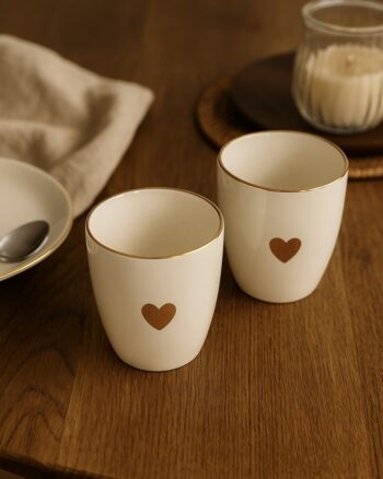 Set de 2 gobelets Matins Câlins Opjet Paris en faïence, avec cœur doré brillant sur table en bois
