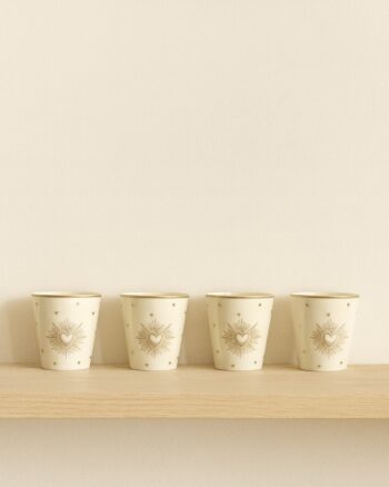 Set de 4 gobelets Ex-Voto doré Opjet Paris sur une étagère en bois clair, en faïence blanche décorée de cœurs dorés.