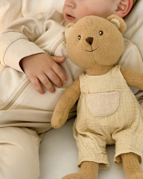 Bébé tenant la peluche Marcel Ours Egmont Toys en salopette beige, doudou doux et rassurant