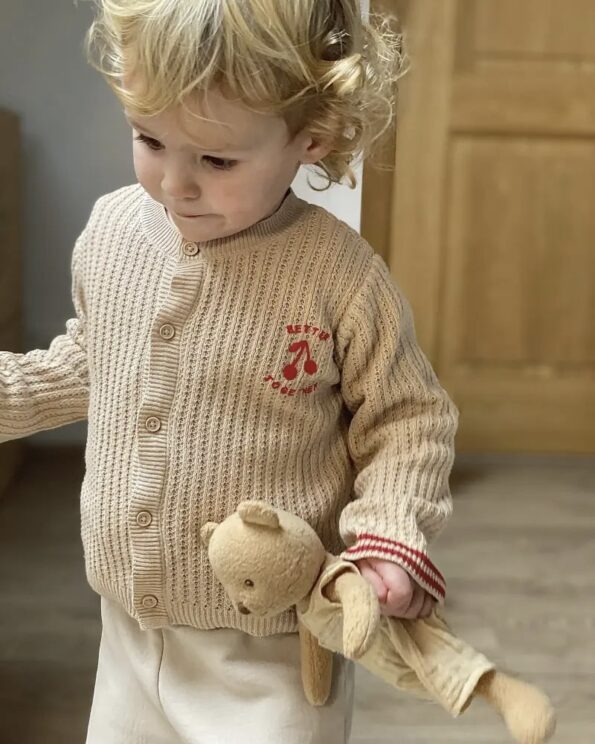 Enfant tenant la peluche Marcel Ours Egmont Toys en salopette beige, compagnon doux et rassurant