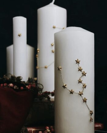 Bijou de bougie Astrology Boncoeurs en laiton doré formant une constellation sur une bougie blanche