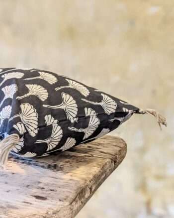 Mini coussin Ginko Boncoeurs imprimé noir et doré posé sur un banc en bois