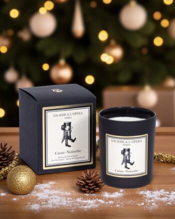 Bougie parfumée Casse-Noisette de la marque Un Soir à l’Opéra, présentée dans son verre noir et sa boîte assortie, posée sur une table décorée pour Noël.