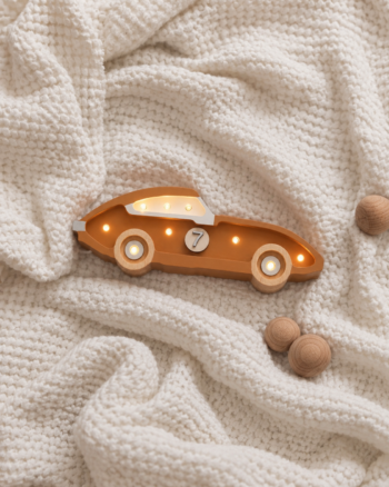 Veilleuse voiture de course Cappuccino Little Lights sur un plaid blanc