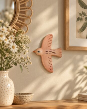 Décoration murale oiseau rose Opjet en céramique sur un mur beige