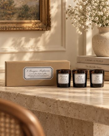 Coffret de 3 bougies parfumées OPJET Paris, Fleur de Lotus, Nuit Étoilée et Thé Vert, présenté sur une console en pierre dans un intérieur élégant.