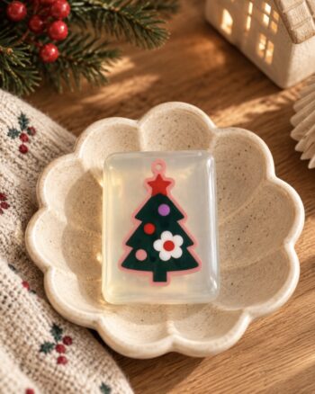 Savon sapin de Noël Ludi Soap transparent dans une coupelle fleur beige avec décoration de Noël.