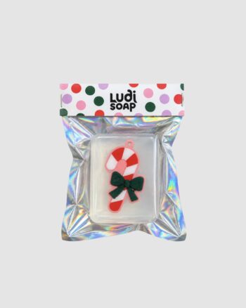 Savon sucre d’orge Ludi Soap transparent avec décoration rouge et blanche et emballage holographique.